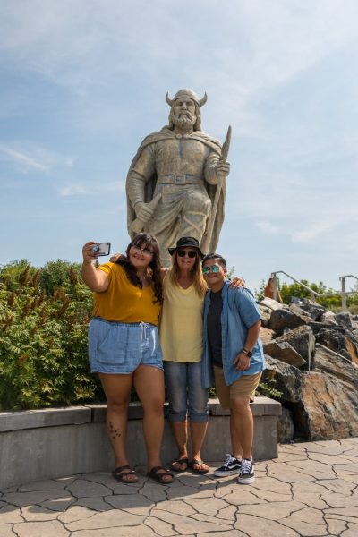 Drei Personen machen ein Selfie vor einer Wikingerstatue in Gimli
