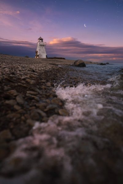 Blick auf das Ufer des Lake Winnipeg mit dem Hecla-Leuchtturm im Hintergrund bei Sonnenuntergang.