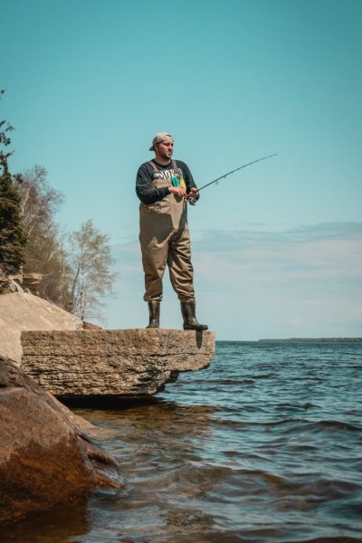 Eine Person angelt von einem Felsen am Rande des Lake Winnipeg im Hecla Provincial Park.