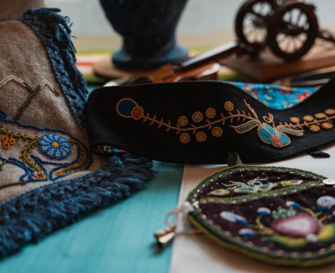 Intricately embroidered textiles and accessories, showcasing vibrant patterns and craftsmanship on a colourful surface.