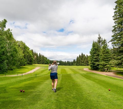 Mujer dando el primer golpe en el campo de golf de Clear Lake.
