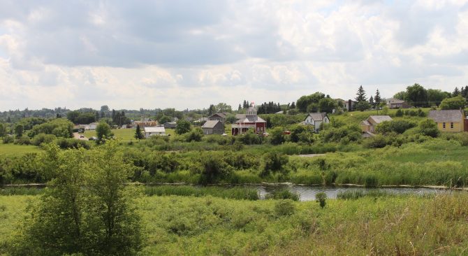 Tanawin ng mga bahay sa gitna ng bush malapit sa isang ilog sa Minnedosa