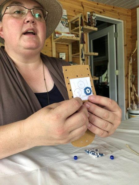 Eine Person hält ein halbfertiges Perlenprojekt hoch