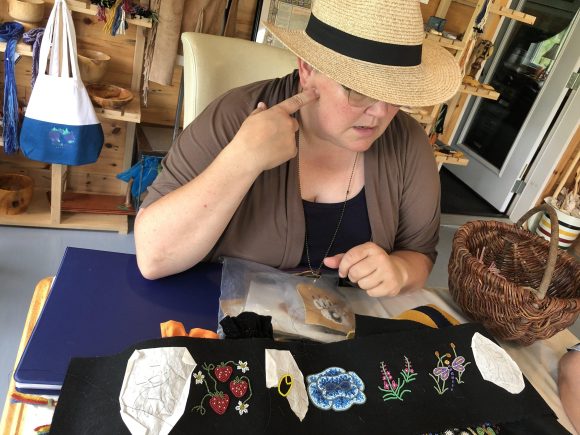 Eine Person sitzt an einem Tisch mit einem halbfertigen Perlenprojekt