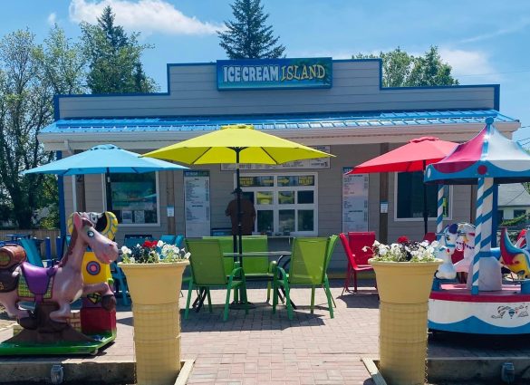 An ice cream shop with blue, yellow and red umbrellas on a pation