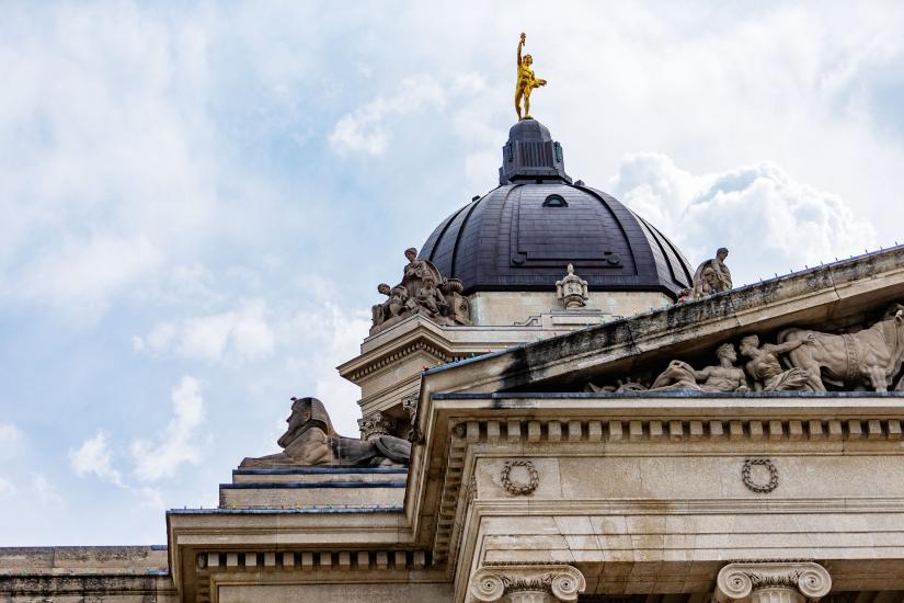 Vue de bas en haut du bâtiment législatif du Manitoba par une journée semi-nuageuse.