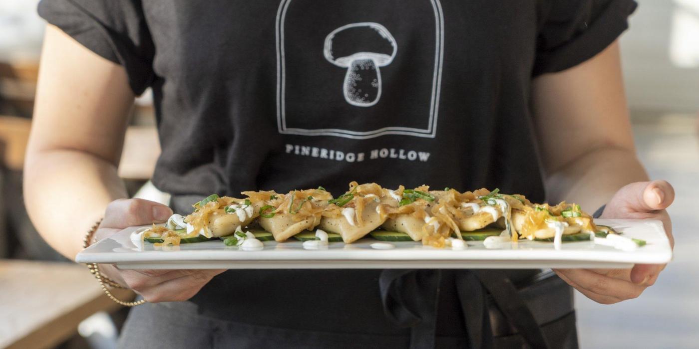 A server carrying a plate of perogies.