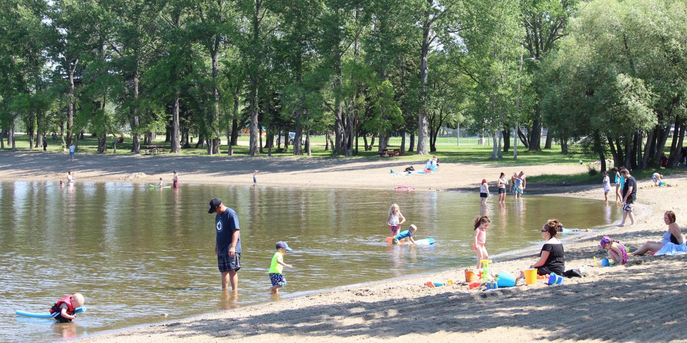 Menschen genießen die Sonne und das Wasser am Strand von Minnedosa.