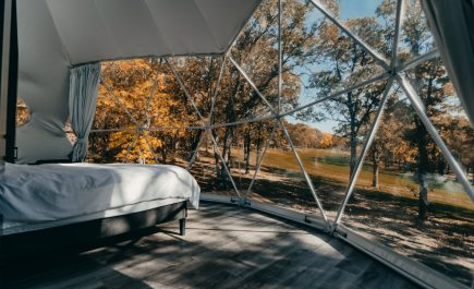 Mirando a través de las amplias ventanas desde el interior de una cabaña de cúpula geodésica en Moonlit Canopies.