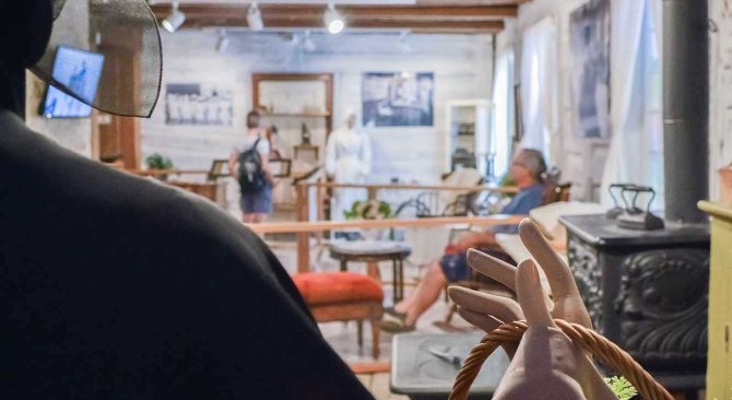Looking over the shoulder of a mannequin at a period exhibit in an old log house.