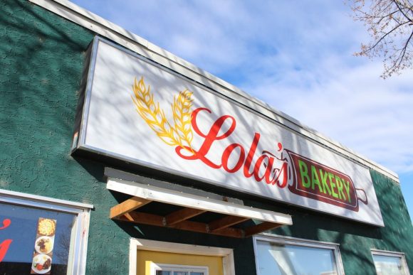 Un cartel que dice "Lola's Bakery" en el exterior de un edificio verde.