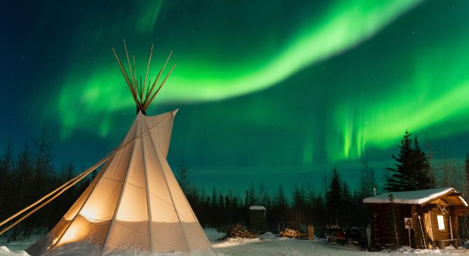 Bright green northern lights dance across the sky above a tipi near Churchill, Manitoba