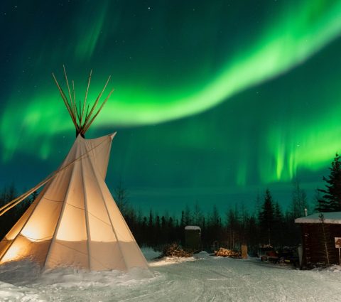 Des aurores boréales d'un vert éclatant dansent dans le ciel au-dessus d'un tipi près de Churchill, au Manitoba.