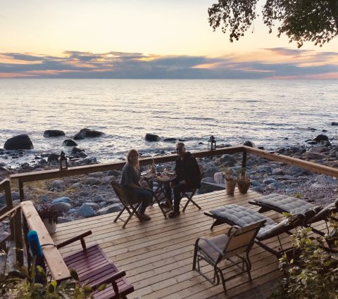Two people eating on a deck overlooking the lake at sunset at Pebble Springs B&B