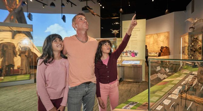 A parent and their children eagerly view a display at the Manitoba Museum Prairies exhibit.