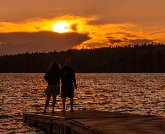 Deux personnes regardent le coucher de soleil depuis l'extrémité d'un quai au lac Clear.