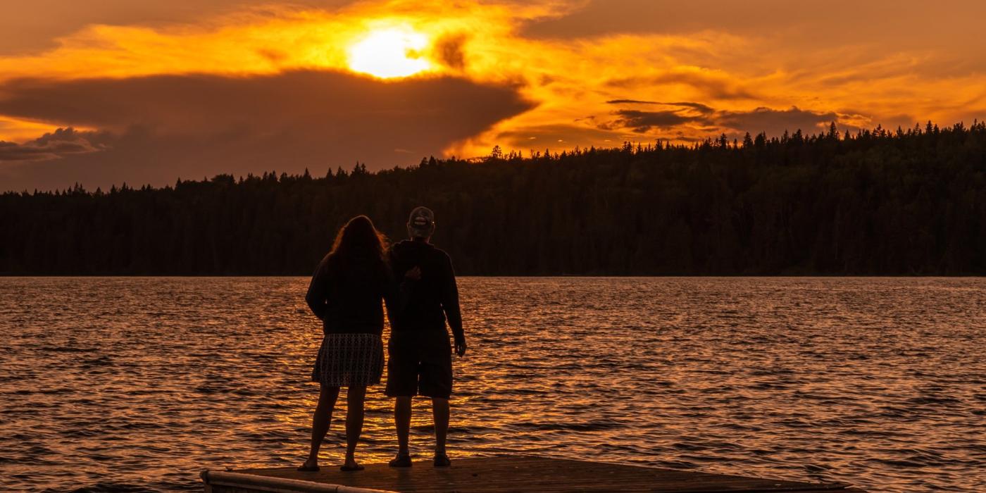 Dos personas contemplan la puesta de sol desde el extremo de un muelle en Clear Lake.