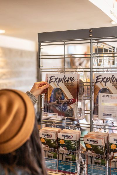 An over the shoulder closeup of a woman picking out a brochure from a rack.