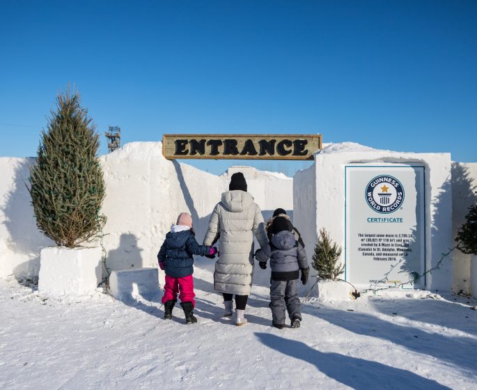 A mother and two children walk hand in hand into the snow maze.