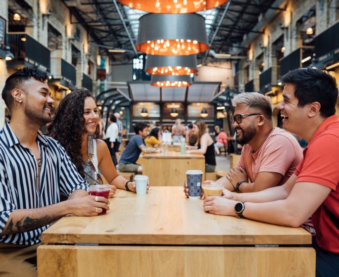 Apat na tao ang umiinom habang nakaupo sa isang mesa sa Common at The Forks