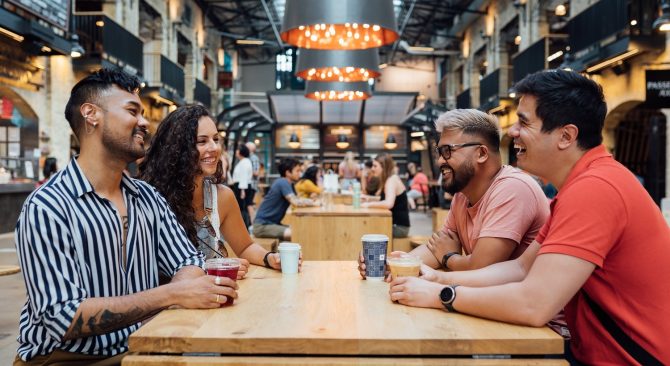 Four people enjoying drinks while seated at a table at the Common at The Forks