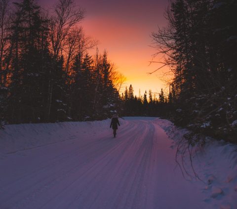 Eine Frau auf einem verschneiten Waldweg bei Sonnenuntergang in The Pas