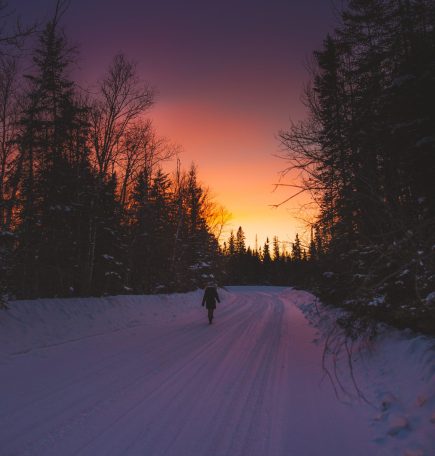 Una mujer camina por un sendero nevado al atardecer en el Pas