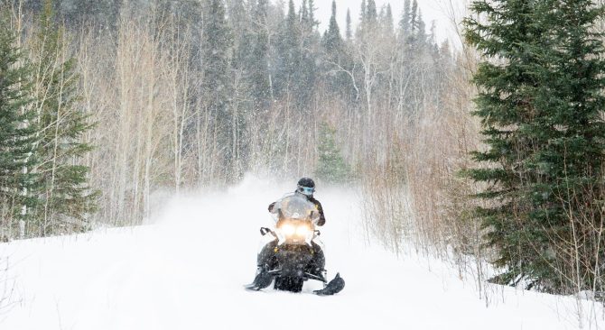 Une personne faisant de la motoneige dans une forêt près de Thompson, au Manitoba