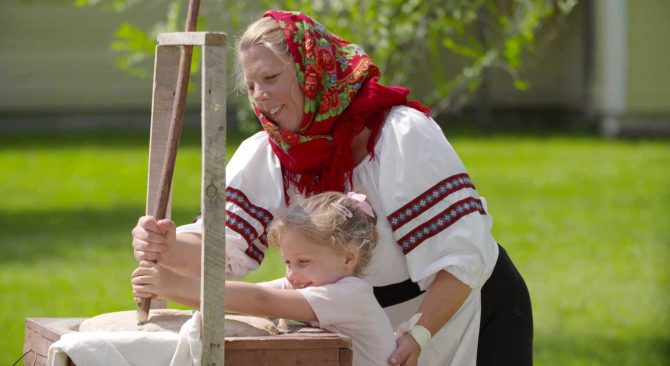 A woman and child making bread using a traditional machine.