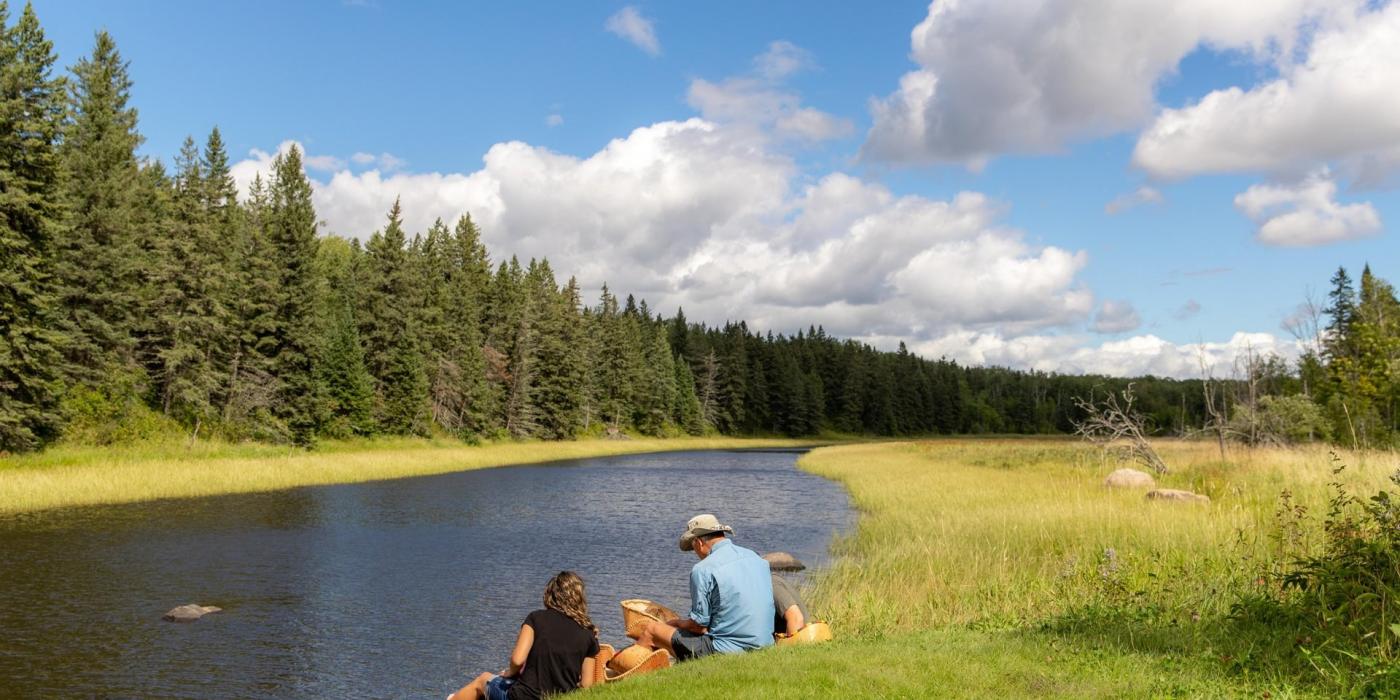 Un couple assis au bord d'un ruisseau dans le parc provincial de Whiteshell