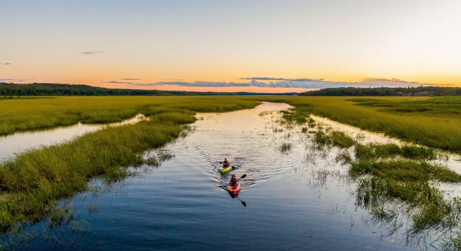 Dos kayakistas disfrutan de un paseo al atardecer en una noche clara y tranquila.