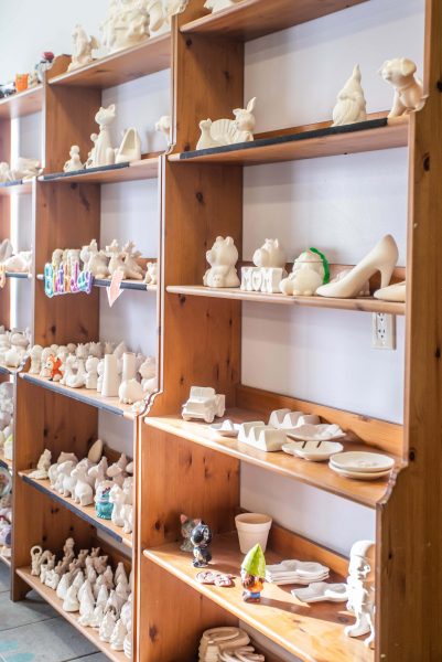 Wooden shelves lined with all different kinds of pieces to be painted.