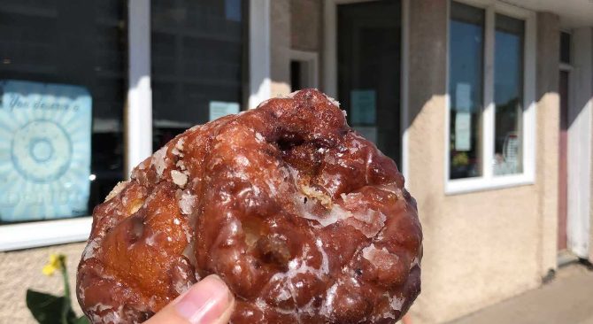 holding up a fritter from Minary Homestyle Bakery in Souris.