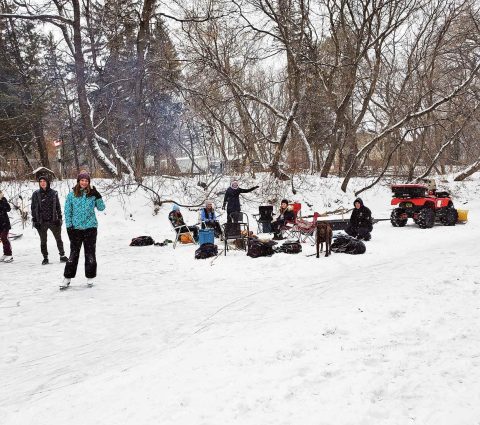 A group of people enjoying a bonfire and skating on an outdoor skating trail.