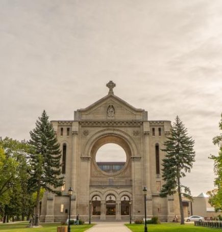 St. Boniface Cathedral surrounded by green trees.