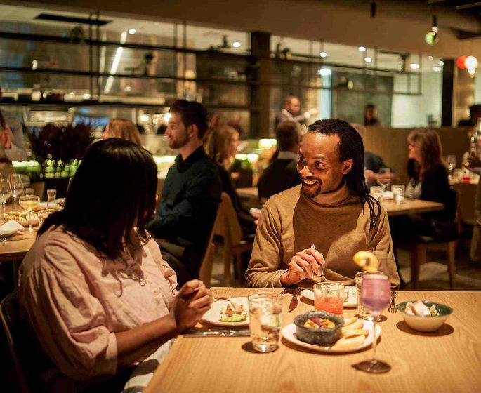 Deux personnes dînant dans la cuisine et le bar Gather, chaleureusement éclairés et accueillants, de l'établissement The Leaf.