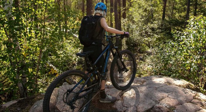 Une personne faisant du VTT dans la forêt baignée de soleil du parc provincial de Whiteshell.