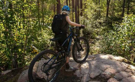A person mountain biking through the sunlit forest in Whiteshell Provincial Park.